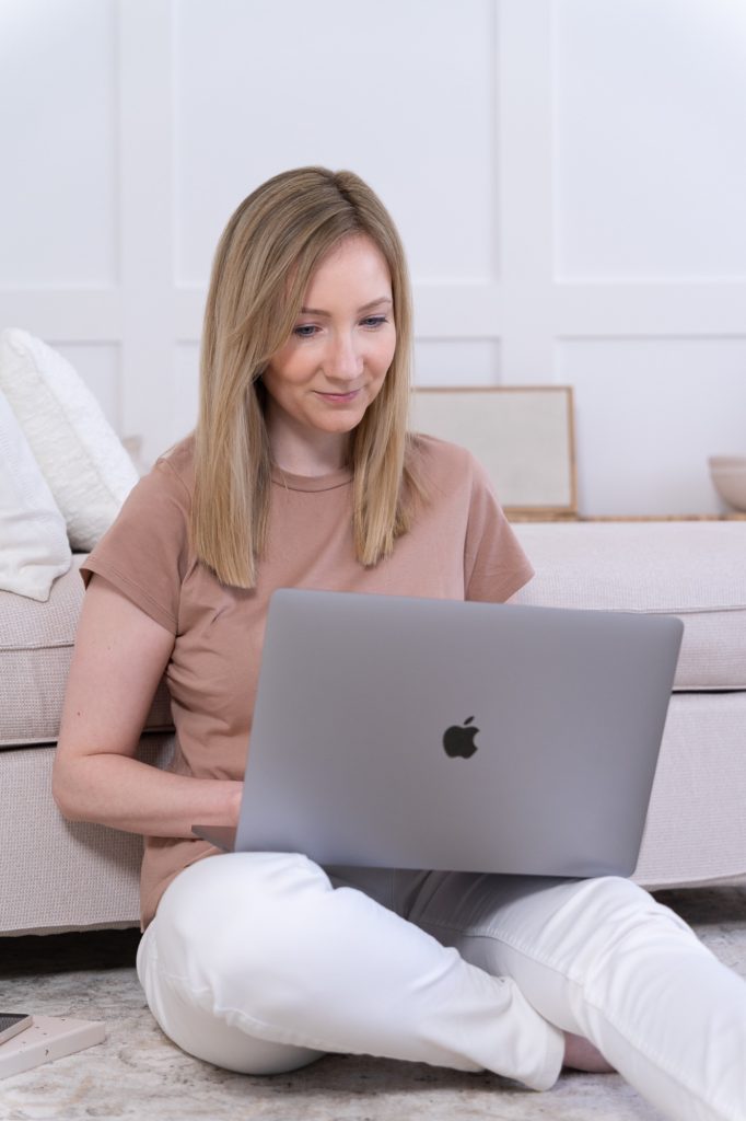 Csilla webdizájner a földön ül a laptopjával, egy kanapé előtt