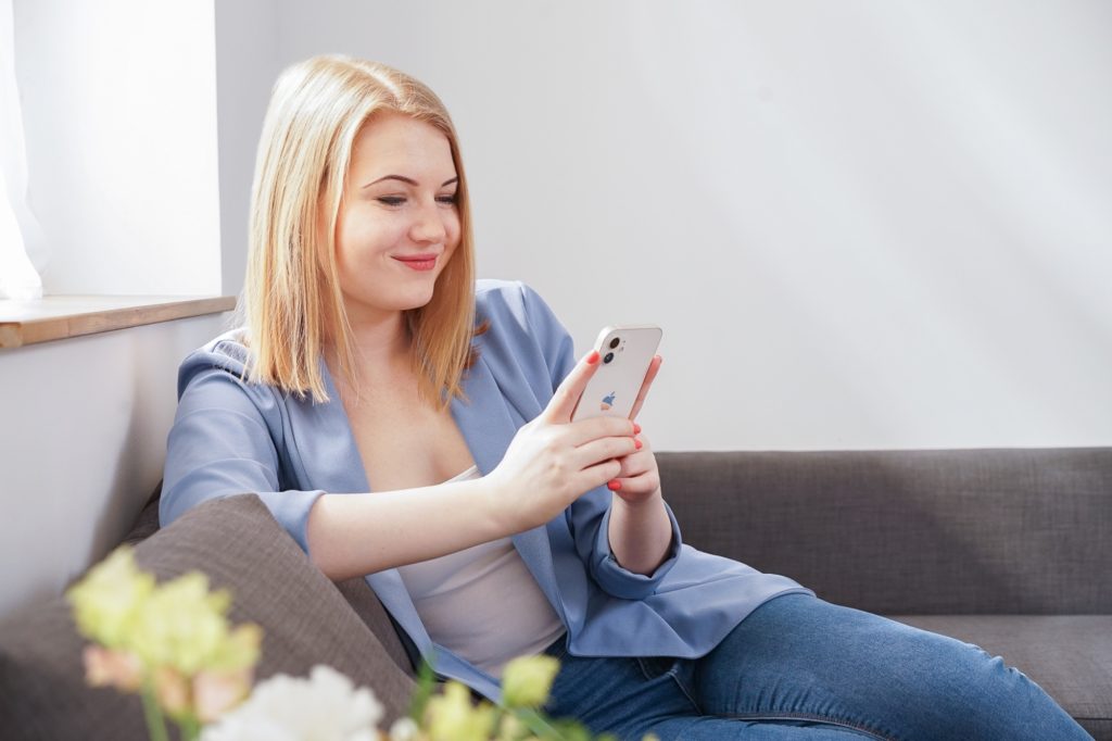 Dóri marketingszakértő a telefonját nézi a kanapén