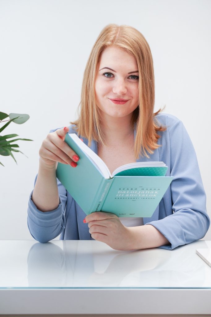 Dóri marketingszakértő könyvvel a kezében mosolyog