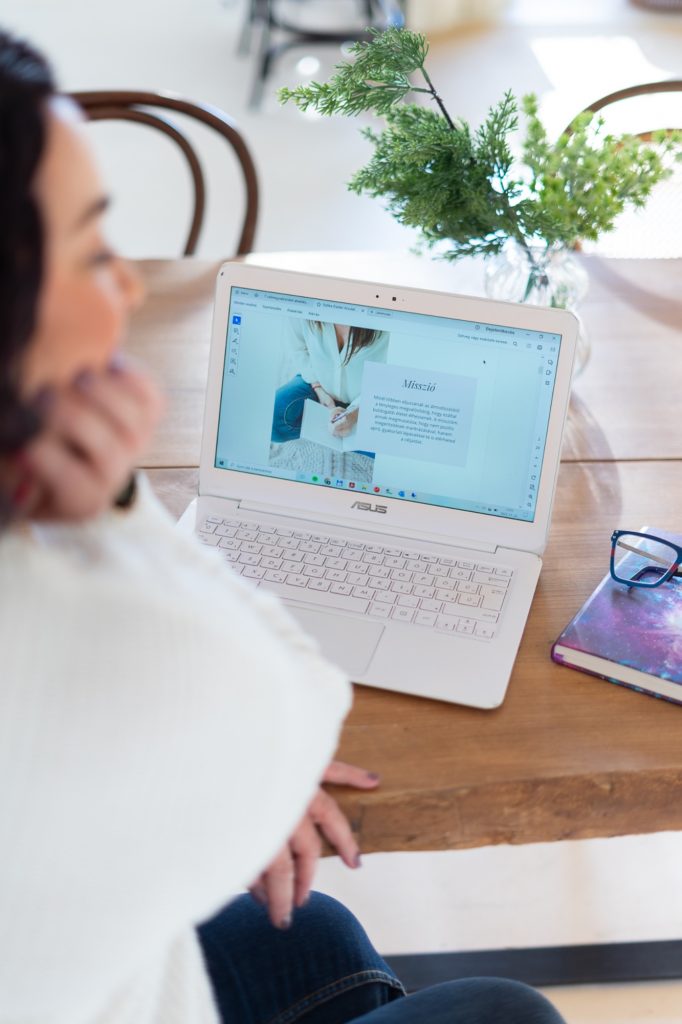 Eszter asztrozófus a laptopja előtt, a képernyőn egy weboldal – weboldal fotózás budapesti stúdióban