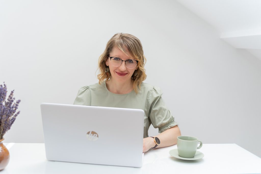 Júlia virtuális asszisztens a laptopja mellett mosolyog