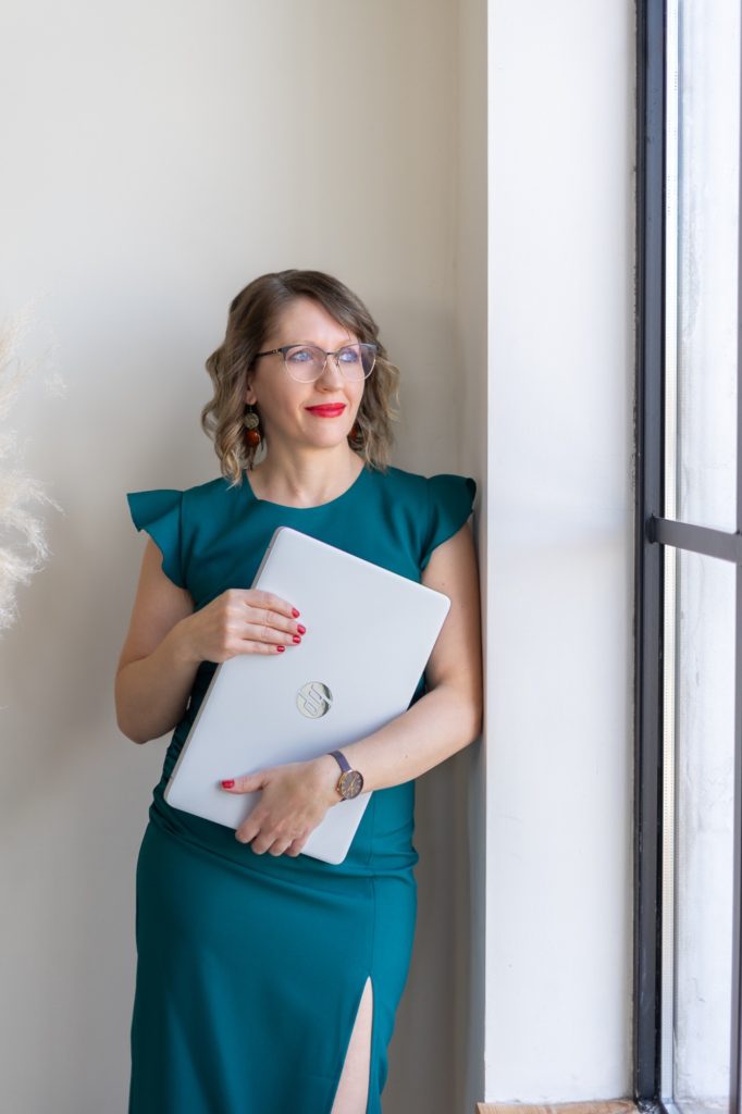Júlia virtuális asszisztens egy mappát tart az ablak mellett
