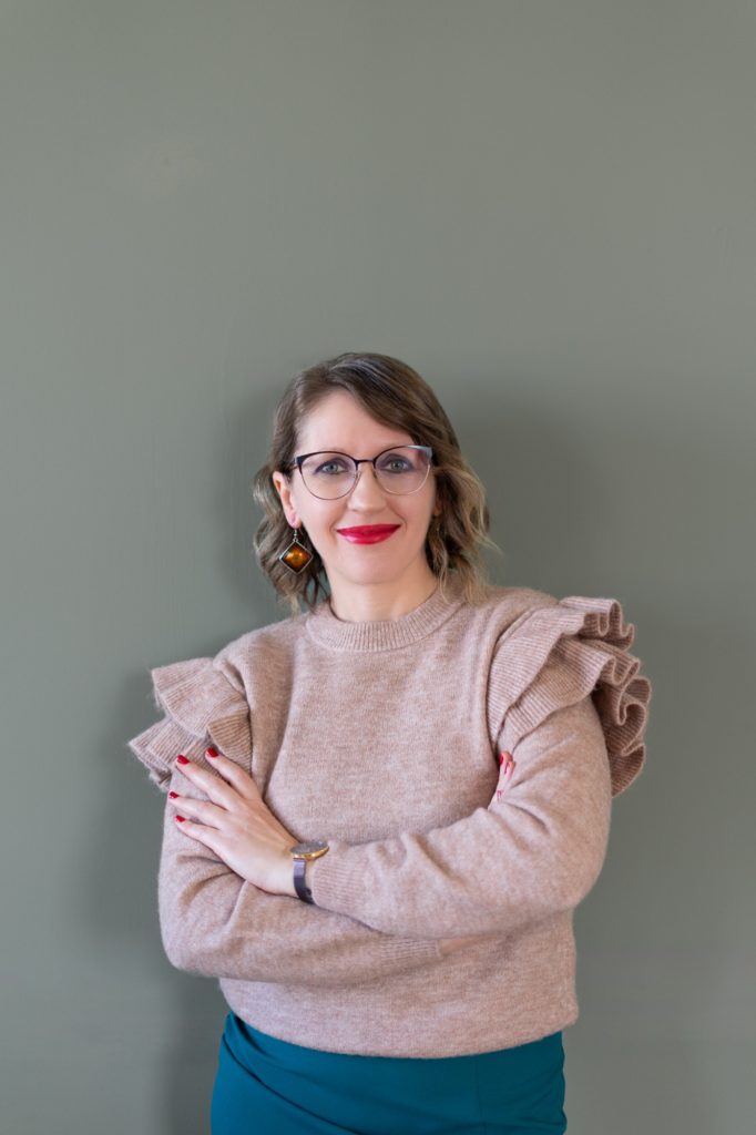 Júlia virtuális asszisztens rózsaszín pulóverben, zöld háttér előtt