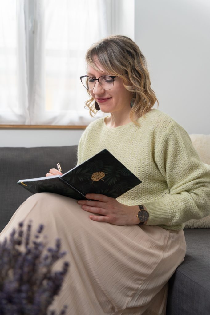 Júlia virtuális asszisztens zöld pulóverben jegyzetel a kanapén – vállalkozás fotózás stúdióban
