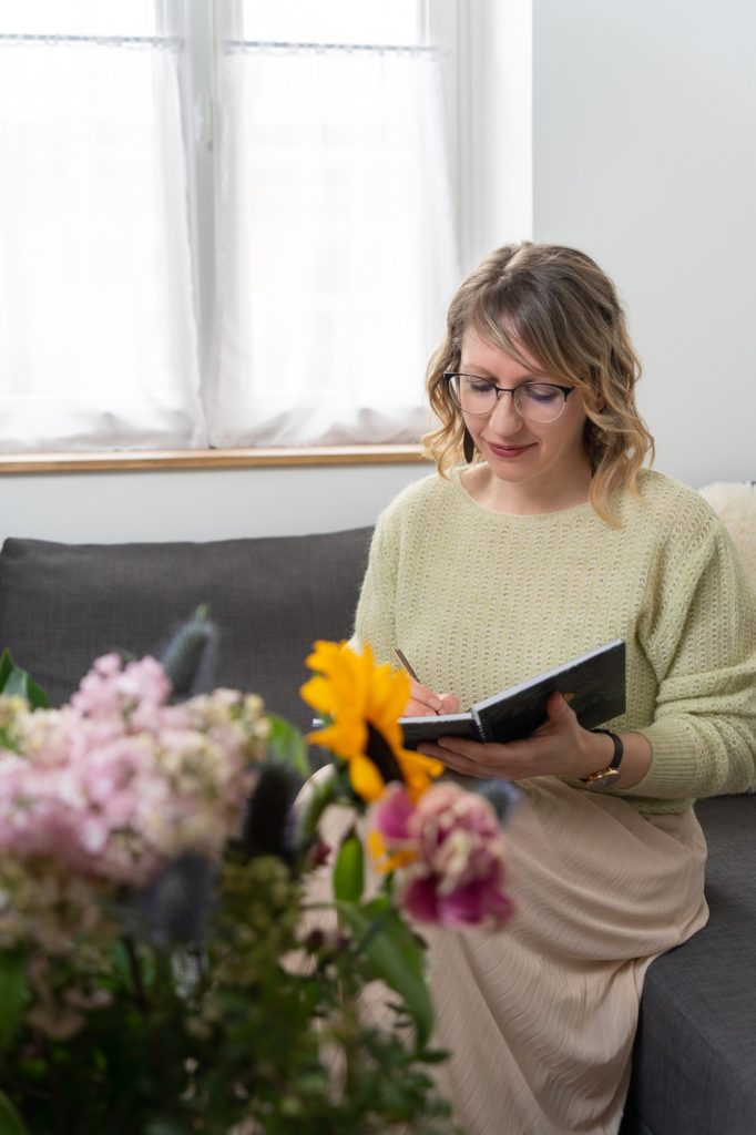 Júlia virtuális asszisztens füzettel a kezében, előtte virágcsokor