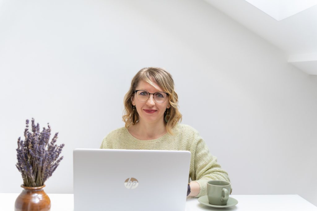 Júlia virtuális asszisztens laptopon dolgozik egy fehér asztalnál