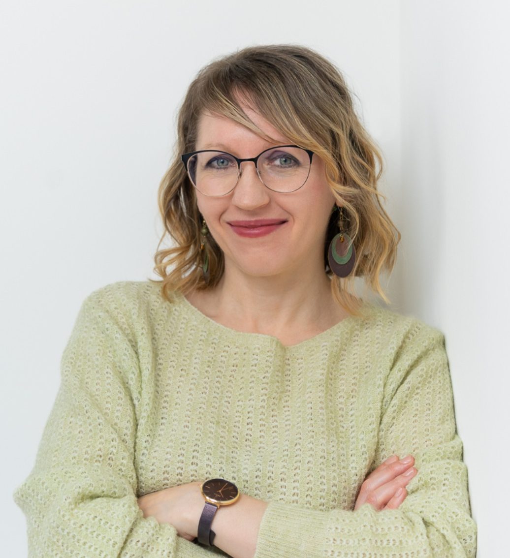 Júlia virtuális asszisztens zöld pulóverben, karba tett kézzel – brand fotózás stúdióban