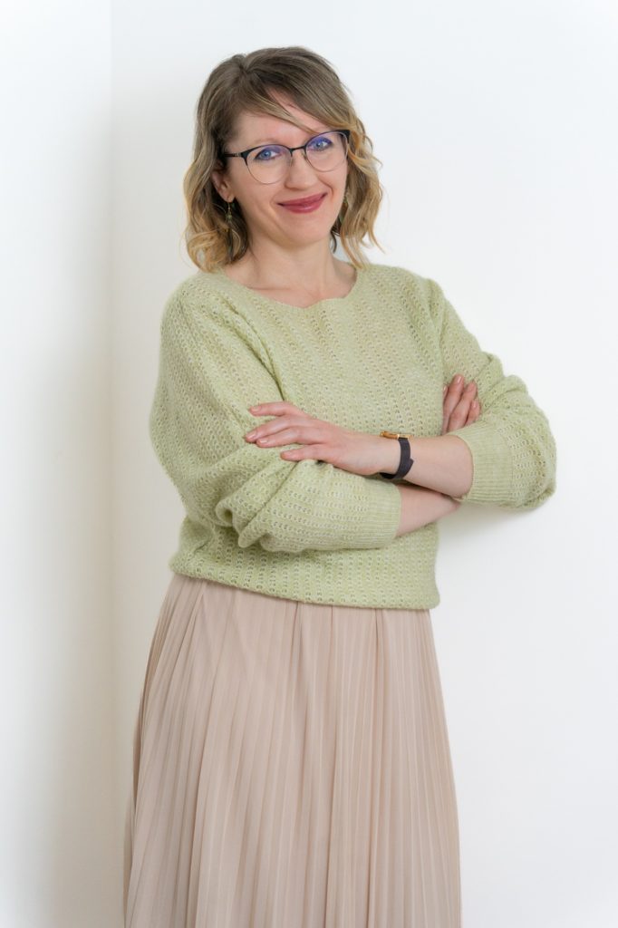 Júlia virtuális asszisztens karba tett kézzel mosolyog