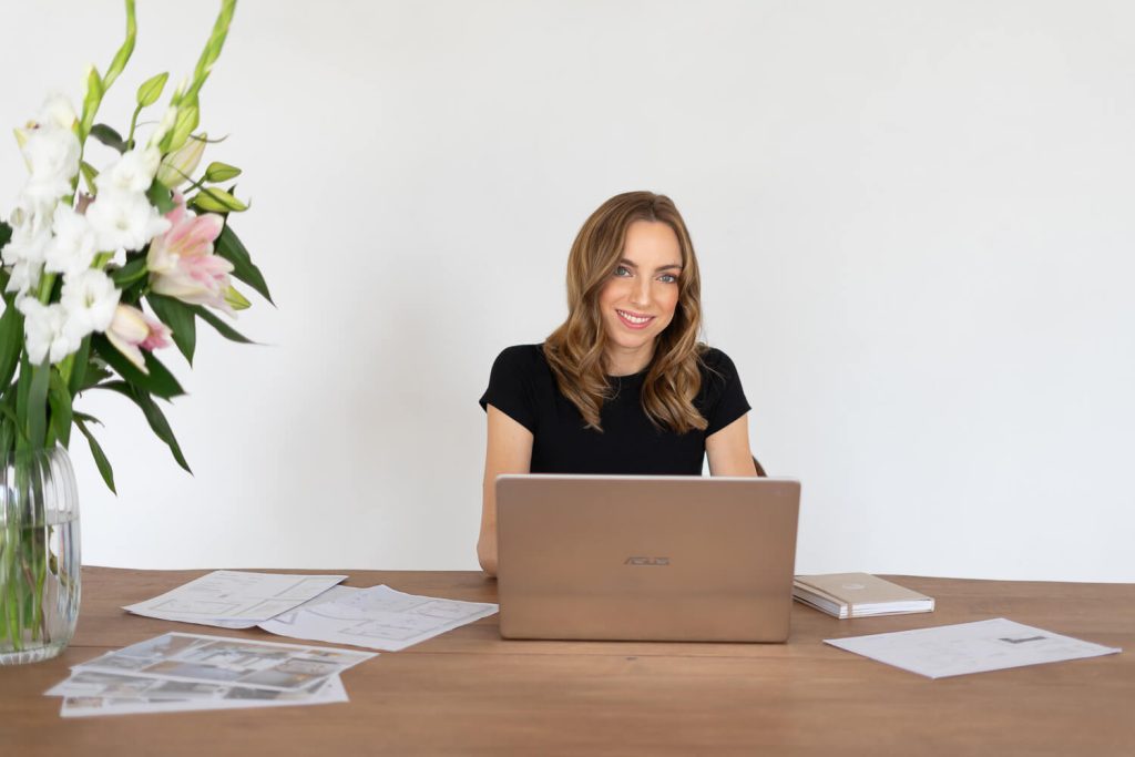 Vállalkozónő fekete felsőben a laptopja előtt, mellette liliomok – business fotózás