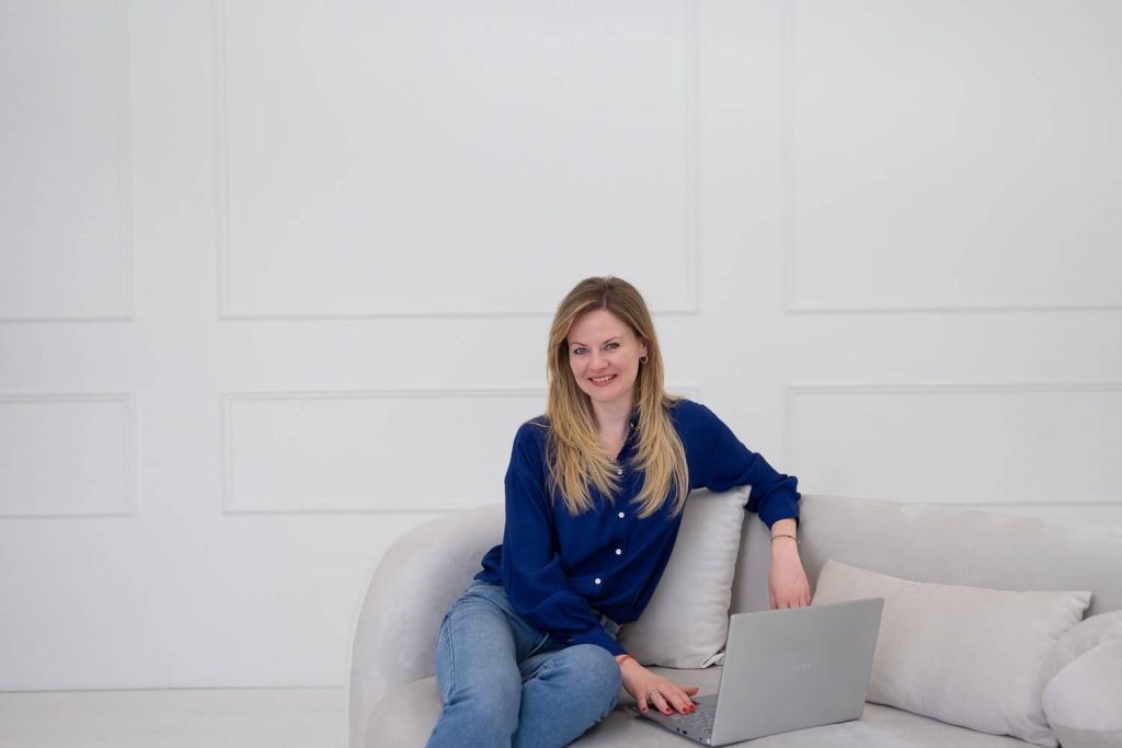 Kinga angoltanár a kanapén ül a laptopja mellett – weboldal fotózás