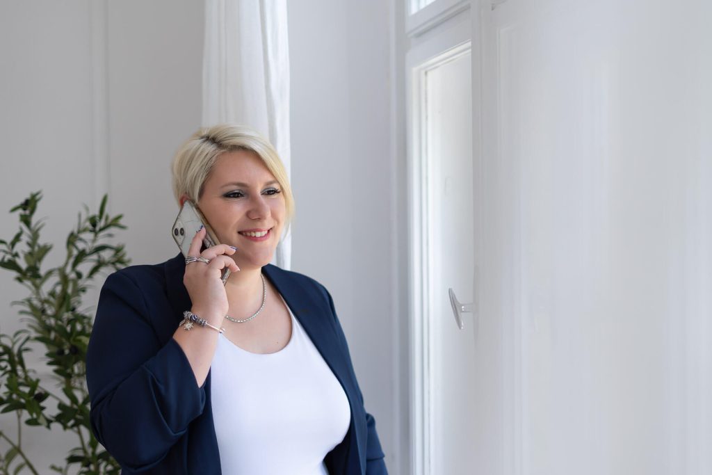 Szőke vállalkozónő sötétkék blézerben telefonál