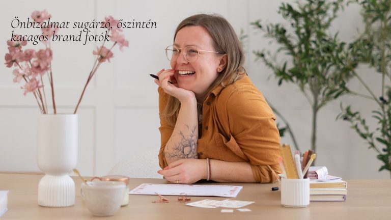 Mosolygó vállalkozónő mustársárga felsőben az asztalra könyököl