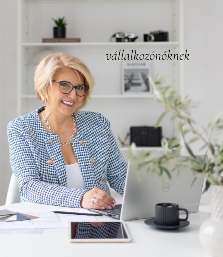 Szőke, szemüveges vállalkozónő kockás blézerben ül a laptopja előtt. Felirat: vállalkozónőknek