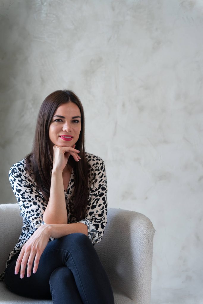 Pszichológus mosolyogva ül egy fotelben, kezét az álla alá téve